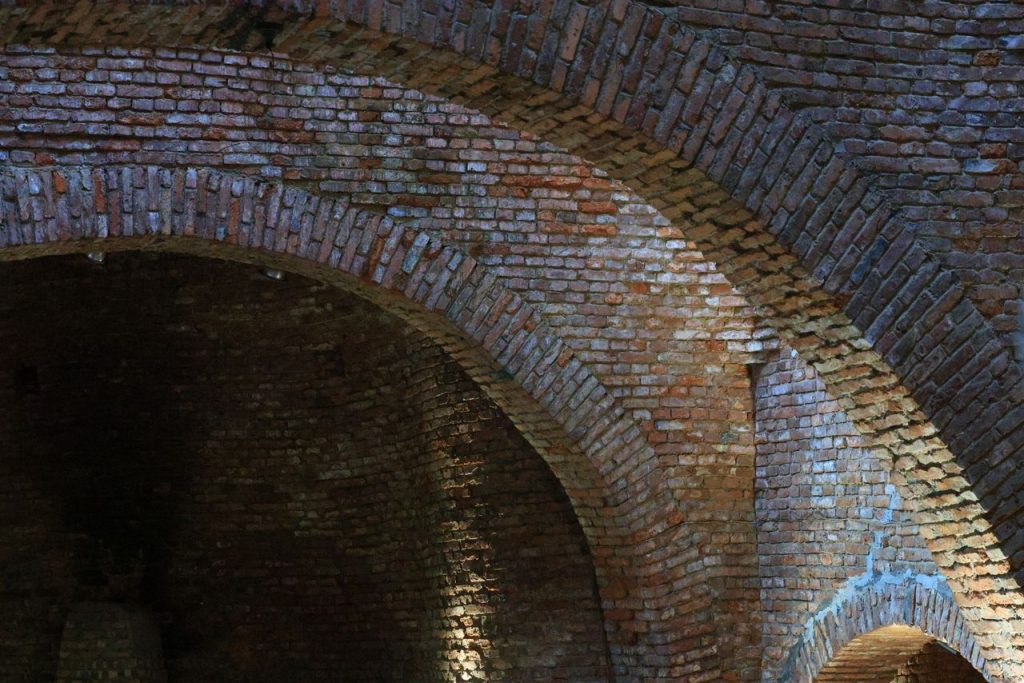 Detailed view of textured brick archways showcasing historical architecture in an underground setting.