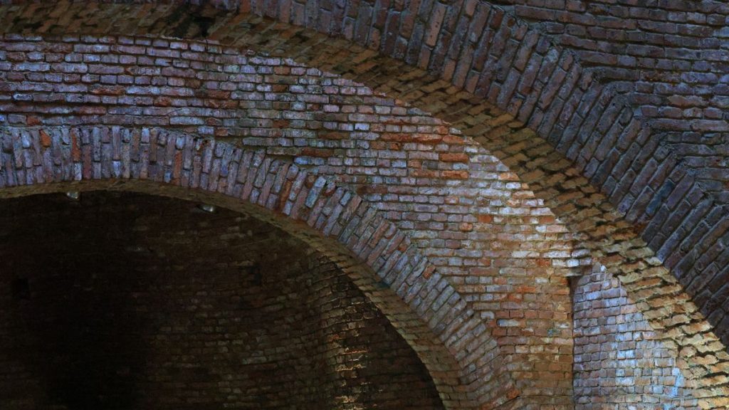 Detailed view of textured brick archways showcasing historical architecture in an underground setting.